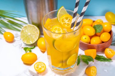 Kumquat lemonade drink. Non-alcohol citrus cocktail with kumquat fruit slices, lime, mint and crushed ice, on sunny background copy space