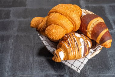 Taze pişmiş kruvasan ve kahve fincanı. Arka planda siyah fayanslı. Üst görünüm kopyalama alanı.