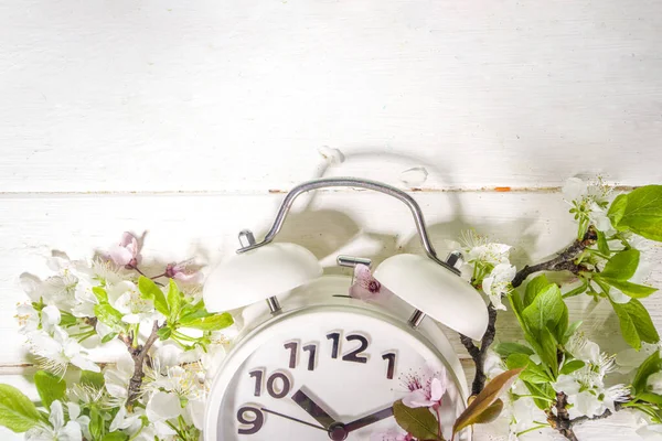 Spring Forward Time, Savings Daylight Concept with Alarm Clock and Spring Garden Flowers on wooden background flatlay copy space on wooden white background