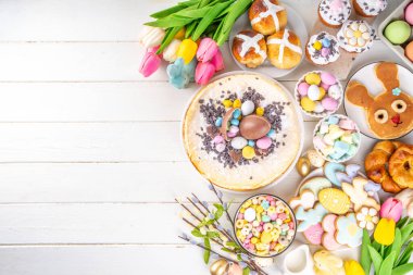 Easter brunch, breakfast food, Kids Easter party buffet. Various traditional Easter sweets, candy, pasties and baking - cross buns, cheesecake, chocolate eggs, pancakes, cupcakes, top view copy space