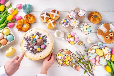 Easter brunch, breakfast food, Kids Easter party buffet. Various traditional Easter sweets, candy, pasties and baking - cross buns, cheesecake, chocolate eggs, pancakes, cupcakes, top view copy space
