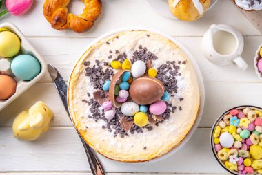 Easter brunch, breakfast food, Kids Easter party buffet. Various traditional Easter sweets, candy, pasties and baking - cross buns, cheesecake, chocolate eggs, pancakes, cupcakes, top view copy space