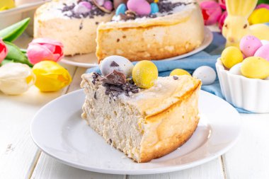 Homemade Easter cheesecake, sweet cottage cheese baking, with Ester chocolate eggs and chocolate drops, with holiday decorations and spring flowers