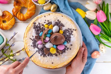 Homemade Easter cheesecake, sweet cottage cheese baking, with Ester chocolate eggs and chocolate drops, with holiday decorations and spring flowers