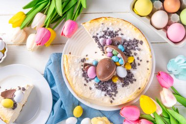 Homemade Easter cheesecake, sweet cottage cheese baking, with Ester chocolate eggs and chocolate drops, with holiday decorations and spring flowers