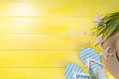 Bright sunny lighted summer vacation background, vacation and travel, beach accessories, swim suit, hat, flip flops, photo camera, sea star and shells on high-colored yellow wooden background top view