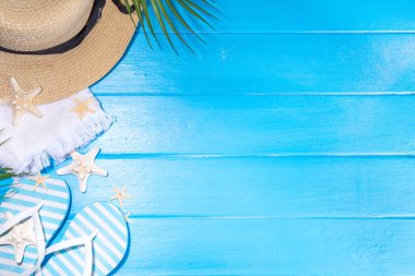 Bright sunny lighted summer vacation background, vacation and travel, beach accessories, swim suit, hat, flip flops, photo camera, sea star and shells on high-colored blue wooden background top view