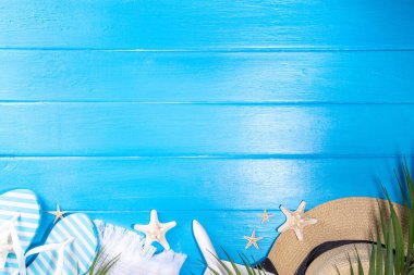 Bright sunny lighted summer vacation background, vacation and travel, beach accessories, swim suit, hat, flip flops, photo camera, sea star and shells on high-colored blue wooden background top view