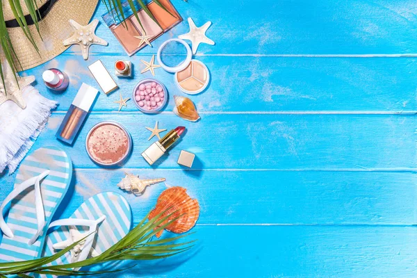 Summer make-up cosmetics flat lay, Vacation, Holiday shopping sale make up.Shadows, lipstick, mascara, face powder, blush on blue wooden background with summer accessories, starfish, shells