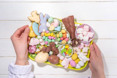 Easter charcuterie board. Sweet Easter party, kids holiday treats assortment - chocolates, easter eggs, marshmallows, candies, chocolate bunny, snacks and treats tray