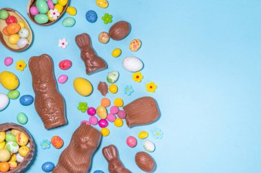 Easter chocolate egg and bunny background. High-colored flat lay with chocolate bunny and rabbits, colorful chocolate eggs. Preparation for Easter, greeting card, Easter sale, top view copy space
