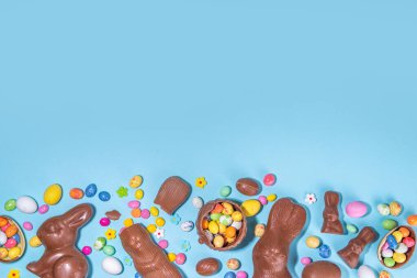 Easter chocolate egg and bunny background. High-colored flat lay with chocolate bunny and rabbits, colorful chocolate eggs. Preparation for Easter, greeting card, Easter sale, top view copy space