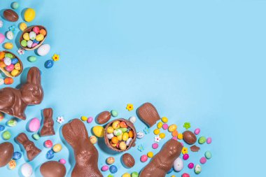 Easter chocolate egg and bunny background. High-colored flat lay with chocolate bunny and rabbits, colorful chocolate eggs. Preparation for Easter, greeting card, Easter sale, top view copy space