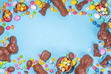 Easter chocolate egg and bunny background. High-colored flat lay with chocolate bunny and rabbits, colorful chocolate eggs. Preparation for Easter, greeting card, Easter sale, top view copy space
