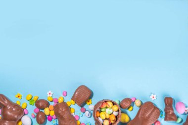 Easter chocolate egg and bunny background. High-colored flat lay with chocolate bunny and rabbits, colorful chocolate eggs. Preparation for Easter, greeting card, Easter sale, top view copy space