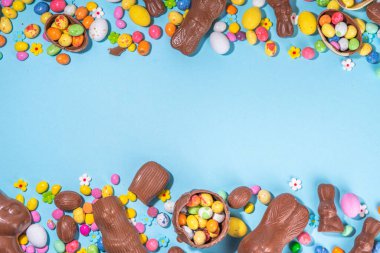 Easter chocolate egg and bunny background. High-colored flat lay with chocolate bunny and rabbits, colorful chocolate eggs. Preparation for Easter, greeting card, Easter sale, top view copy space