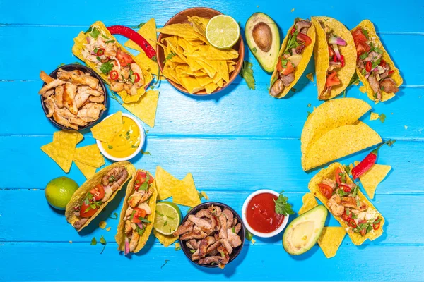 Traditional Mexican street food, fast food background, corn Taco, nachos with meat, vegetables, avocado, beans, corn, salsa. Served with various sauces. Mexican holiday flatlay