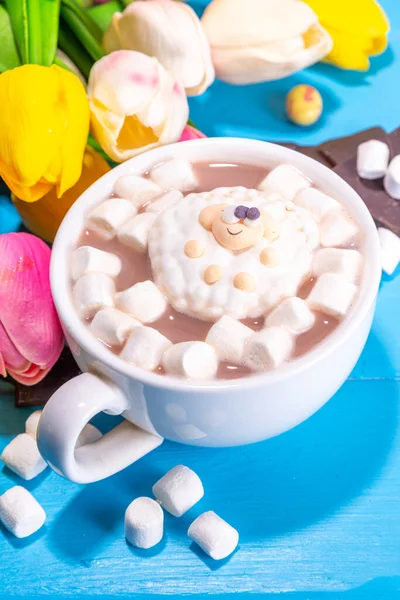 Funny Easter hot chocolate with Easter. Funny hot chocolate with easter symbols - rabbit feet, rabbit, flowers, marshmallow lamb. Cute cocoa recipe idea for Easter kids party