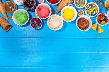 Ice cream festival background, Summer ice cream buffet with various gelato sundaes flavors. sweet toppings and sprinkles, high-colored blue wooden background to view copy space