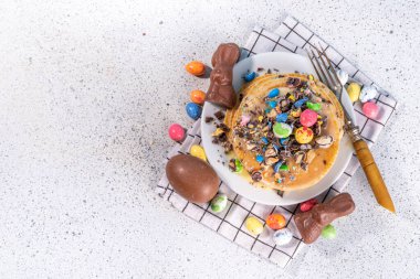 Easter sweets and candies background. High-colored blue flat lay with various Easter chocolate eggs, treats, symbols of easter sheep, bunny, carrot, flowers, cookies, top view copy space, frame