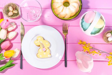 Easter sweets and candies background. High-colored blue flat lay with various Easter chocolate eggs, treats, symbols of easter sheep, bunny, carrot, flowers, cookies, top view copy space, frame