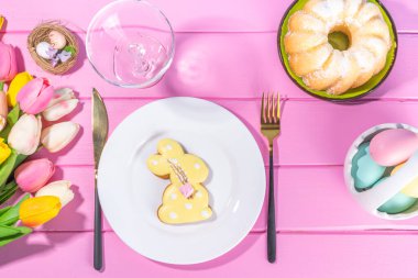 Easter sweets and candies background. High-colored blue flat lay with various Easter chocolate eggs, treats, symbols of easter sheep, bunny, carrot, flowers, cookies, top view copy space, frame