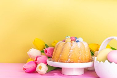 Easter sweets and candies background. High-colored blue flat lay with various Easter chocolate eggs, treats, symbols of easter sheep, bunny, carrot, flowers, cookies, top view copy space, frame