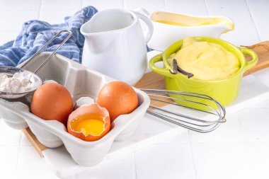 Malzemeli ev yapımı krema. Vanilya, süt ve yumurta. Tatlı krema beyaz mutfak masasının fotokopi masasında tatlı pişirme arkaplanı. 