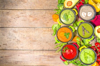 Çeşitli renkte sebze çorbaları. Küçük porsiyonlu kuşkonmaz, ıspanak, brokoli, yeşil bezelye, domates, havuç gibi çeşitli sebze kremalı çorbalar. Ahşap arkaplan kopyalama alanı üst görünümü