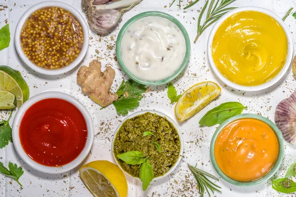 Assortment of different classic sauces and dips in sauceboats. Mayonnaise, ketchup, tartare, mustard, pesto, sour cream, barbecue sauces with spices, herbs, lemon