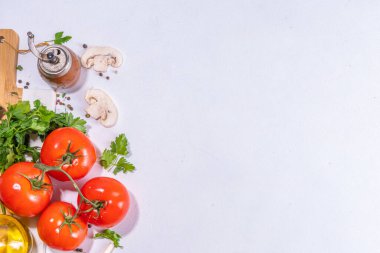 Cooking background with vegetable ingredients. Healthy dinner preparation flat lay, with fresh raw tomatoes, onion, garlic, herbs and greens, olive oil, salt, pepper seasonings, on white background 