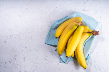 Sweet ripe raw bananas on white kitchen table, copy space