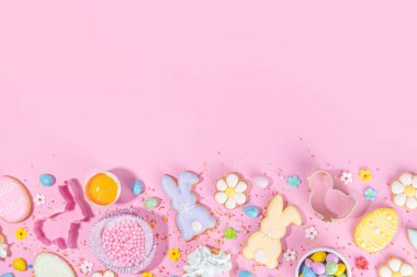 Cute pink sweet baking flat lay for Easter holiday. Cooking background with baking ingredients, rolling pin, whisk for whipping, cookie and cutters, sugar sprinkling, flour, top view copy space 