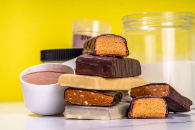 Çeşitli enerji protein çubukları. Protein çubukları ve abur cuburların farklı tadı, protein tozu kavanozu ile yüksek renkli arkaplan kopyalama alanı