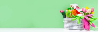 Yüksek renkli pastel arka planda bahar çiçekleri olan temizlik malzemeleri ve çatal bıçakları. Bahar evi temizlik konsepti. Kadın elleri sprey deterjan tutuyor, temizlik eldivenleri ve mendillerle.