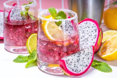 Pitaya, ejderha meyvesi, limon ve naneli renkli tropikal kokteyl. Tuzlu margarita alkollü pitahaya meyveli içecek. Arka planda kiremit fotokopi alanı. 