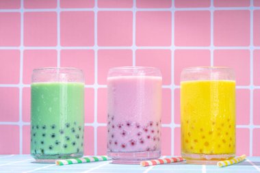 Renkli yaz köpüklü çay seti, parlak kremalı inci çayı ya da latte tapyoka içecekleri, pembe dut, sarı turunçgil, yeşil nane, tapyoka topları ve ezilmiş buz rengarenk arka planda