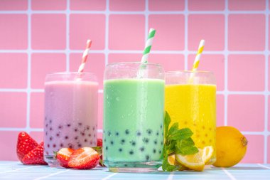 Renkli yaz köpüklü çay seti, parlak kremalı inci çayı ya da latte tapyoka içecekleri, pembe dut, sarı turunçgil, yeşil nane, tapyoka topları ve ezilmiş buz rengarenk arka planda