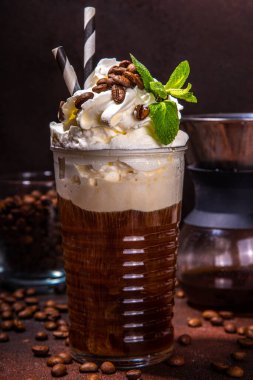 Büyük bardakta buzlu kahve. Krem şantili bir soğuk latte, koyu kahverengi arka plan fotokopi alanı üzerine kahve makinesi.