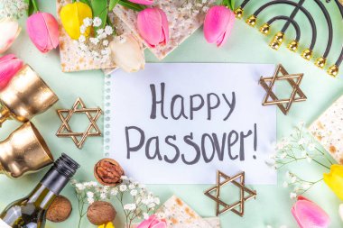 Passover, Pesah background. jewish Easter Passover spring holiday celebration, with accessories - menorah, matzo, spring flowers, wine bottle, gold wine glass, jewish david stars, copy space top view 