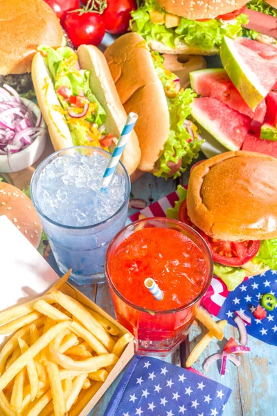 7月4日 アメリカ独立記念日のコンセプト 愛国的で伝統的なアメリカ料理 スイカ ハンバーガー ホットドッグ 飲み物 青い木製の屋外テーブルの背景を持つピクニックパーティー — ストック写真