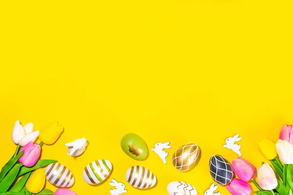 明亮的复活节贺卡背景 色彩艳丽的黑色 条纹彩绘复活节彩蛋 白色兔子装饰 郁金香花在五颜六色的黄色背景上 平坦的外层复制空间 — 图库照片