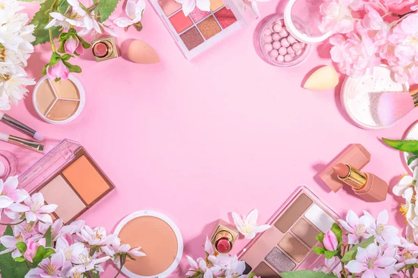 Spring professional makeup flat lay. Spring make up set on pink background. Different make-up cosmetics, beauty accessories flat lay with spring blossom flowers top view copy space