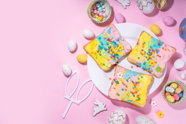 Çocuklar için tatlı ve komik Paskalya kahvaltısı. Ev yapımı gökkuşağı renkli sandviçler, renkli krem peynirli sandviçler ve şeker parçacıkları.