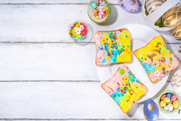 かわいい甘くて面白い子供のためのイースターの朝食 自家製の虹色のサンドイッチ 色のクリームチーズと砂糖のスプリンクル付きサンドイッチ — ストック写真