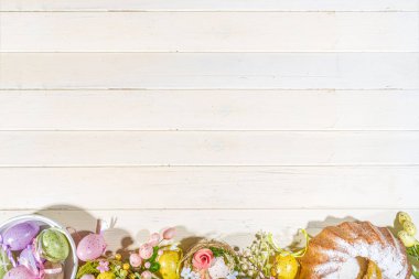 Paskalya 'da renkli pastel yumurtalar sepetin içinde, hafif ahşap arka planda tüyleri olan. Paskalya tebrik kartı kompozisyonu, bahar tatili durgun yaşam geçmişi