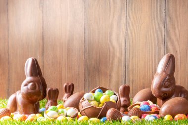 Paskalya yumurtası avcılığı geçmişi. Çeşitli şeker ve çikolatalı Paskalya yumurtası, tavşancık ve tavşanlar yeşil çimen parkında ya da bahçe arka planında yumurta sepeti