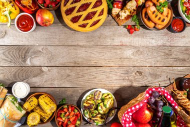 Çeşitli piknik barbekü yemekleri ve flatlay içiyorlar. Yaz bbq piknik yemekleri, ızgara etler, kebaplar, sebzeler, meyve salatası, geleneksel piknik pastası, sandviçler, üst görünüm fotokopi alanı.