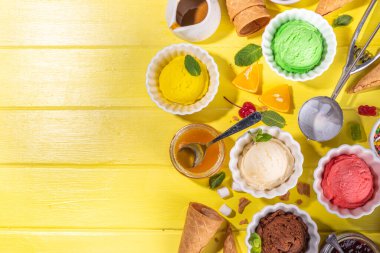 Ice cream festival background, Summer ice cream buffet with various gelato sundaes flavors. sweet toppings and sprinkles, high-colored yellow wooden background to view copy space