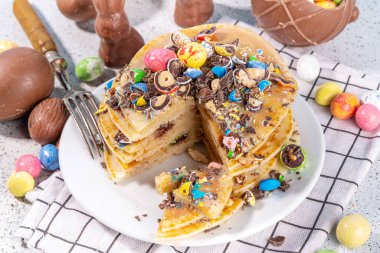 Paskalya için çocukların komik şirin kahvaltısı. Amerikan gözlemeleri, çikolatalı kızarmış hamur kekleri, çikolatalı yumurtalar, marşmelovlar, üzerine çikolata parçacıklı şeker serpiştirilmiş dekorlar.